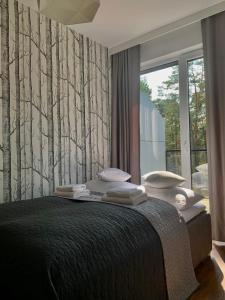 a bedroom with a bed with trees on the wall at REMAR - Apartamentai prie Necko Ežero in Augustów