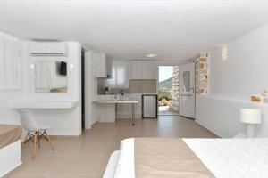 a white bedroom with a bed and a kitchen at Irini's house with Jacuzzi in Dhragoulás