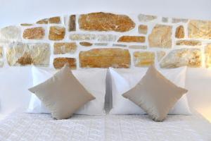 a group of pillows on a bed with a stone wall at Irini's house with Jacuzzi in Dhragoulás
