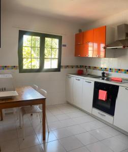 a kitchen with white cabinets and a table and a window at Royal Park Guesthouse in Corralejo