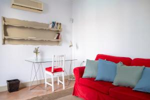 un soggiorno con un divano rosso e un tavolo di EXCLUSIVA CASA EN EL CENTRO HISTORICO de SEVILLA a Siviglia Altre 23 foto