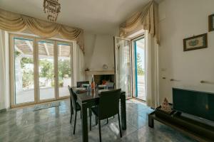 a dining room with a table and chairs and windows at Calaluna - Villa Sea View by Diddoi in Leuca