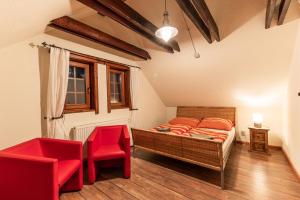 een slaapkamer met een bed en twee rode stoelen bij Pivovar BUC Kvačany in Kvačany