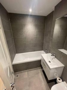 a bathroom with a tub and a toilet and a sink at Marvellous New Build 2 Bed Flat - 1 Ophelia Court in Epsom