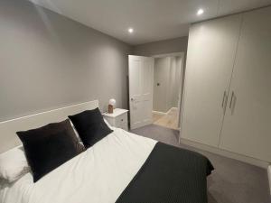 um quarto com uma grande cama branca com almofadas pretas em Marvellous New Build 2 Bed Flat - 1 Ophelia Court em Epsom