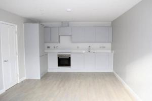 a white kitchen with white cabinets and a wooden floor at Marvellous New Build 2 Bed Flat - 1 Ophelia Court in Epsom