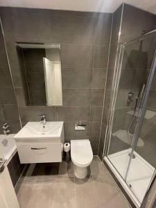 y baño con aseo, lavabo y ducha. en Marvellous New Build 2 Bed Flat - 1 Ophelia Court en Epsom