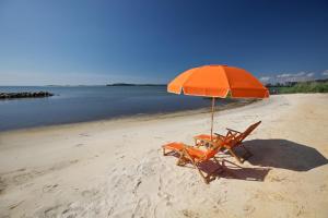 uma cadeira de praia com um guarda-sol laranja numa praia em Sun Outdoors Cape Charles em Cape Charles
