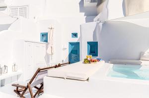 a white room with a swimming pool and a table and chairs at Aristos Life Luxury Cave Villas in Oia