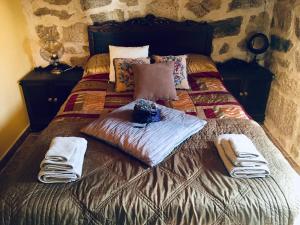 1 cama con 2 almohadas y toallas en Casa rural Buxo Ribeira Sacra, en Carballedo