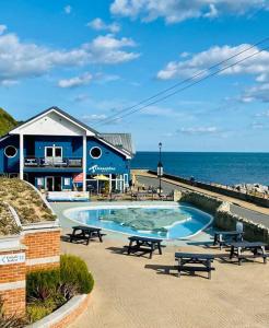 a swimming pool with picnic tables in front of the ocean at Peaceful Coastal Apartment in Ventnor
