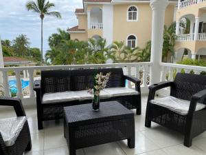 a patio with chairs and a table with a vase of flowers at Picturesque Ocean View Condo in San Felipe de Puerto Plata