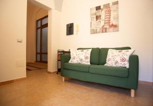 a green couch with two pillows in a living room at Sogni a Sud - The Fab Stay in Mesagne