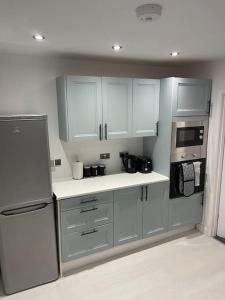 a kitchen with white cabinets and a stainless steel refrigerator at ED Colchester House in Colchester