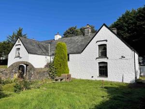 an old white house with a grass yard at Large Historic Farmhouse in Rhondda Valley Perfect for Groups with Hot Tub in Blaencwm