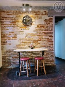 a table with two stools in front of a brick wall at La Maison de Nicole in Mousseaux-sur-Seine