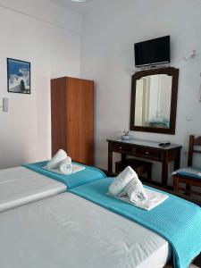 two twin beds in a room with a mirror at Anna Maria Rooms Santorini in Perissa