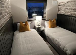 2 Betten in einem kleinen Zimmer mit Fenster in der Unterkunft Wolf Inn Serviced Accommodation in Lowestoft