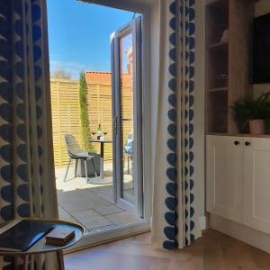 una puerta corredera de cristal que conduce a un patio con mesa en Wheelwright's Rest, Legbourne, Louth, en Louth