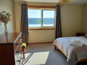 a bedroom with a bed with a dresser and a window at Spacious Sea View Home 5 miles from Inverness in North Kessock