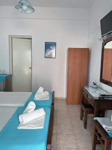 a room with two beds and a sink and a desk at Anna Maria Rooms Santorini in Perissa