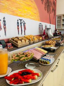 a buffet line with plates of food and drinks at Hotel Rosa da Ilha - Pertinho do Mar com piscina in Guarujá