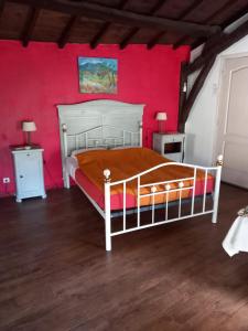 - une chambre avec un lit blanc et un mur rouge dans l'établissement Les Cèdres Bleus de Joany, à Viviez
