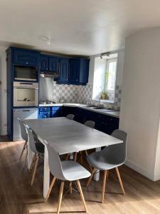 Grande maison conviviale في فونتيناي لو كومت: مطبخ مع دواليب زرقاء وطاولة وكراسي