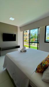1 dormitorio con 1 cama blanca grande y TV de pantalla plana en Aloha A15, en Ipojuca