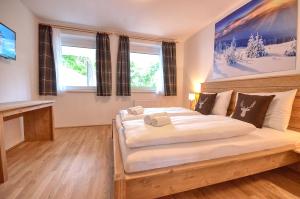 een slaapkamer met een groot bed met witte lakens bij Apartment Snowmountain - by Alpen Apartments in Zell am See