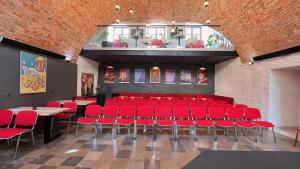 Hotel77 في زاموسك: غرفة مع كراسي حمراء وطاولات في مبنى