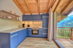 a kitchen with blue cabinets and a balcony at Ski-in Ski-out Chalet Maiskogel 17C - by Alpen Apartments in Kaprun