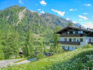 a building on a hill with mountains in the background at Haus Kitzsteinhorn 6 - by Alpen Apartments in Kaprun