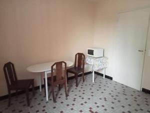 a kitchen with a table and chairs and a microwave at Appartement face à l'église, idéal étape, confort basique in Vatan