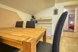 une salle à manger avec une table en bois et des chaises noires dans l'établissement Apartment Lisa - by Alpen Apartments, à Zell am See