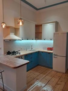 een keuken met blauwe kasten en een witte koelkast bij Home away from home in Tbilisi City