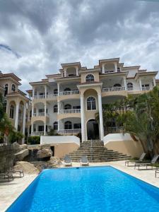 a large house with a swimming pool in front of it at Picturesque Ocean View Condo in San Felipe de Puerto Plata