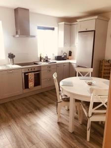 a kitchen with a white table and a table and chairs at Lakeview Holiday Home Whitegate in Whitegate