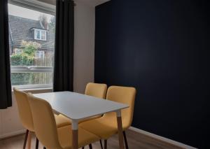 a dining room with a white table and yellow chairs at Cottenham - City Centre with Free Private Parking 2 toilets 4 Bedroom Sleeps 8 in Newcastle upon Tyne