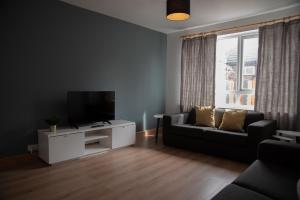 a living room with a couch and a tv at Cottenham - City Centre with Free Private Parking 2 toilets 4 Bedroom Sleeps 6 in Newcastle upon Tyne