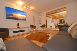 a living room with a couch and a tv on the wall at Haus Thumersbach - by Alpen Apartments in Zell am See
