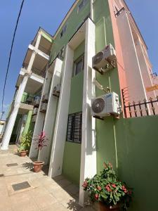 a green and white building with plants in front of it at Janneya Apartments in Sukuta