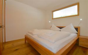 a bedroom with a bed with white sheets and a window at Sonnenhaus A - by Alpen Apartments in Zell am See