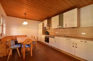 ツェル・アム・ゼーにあるSki-in Ski-out Chalet Kriekels - by Alpen Apartmentsの木製の天井、テーブル付きのキッチンが備わります。