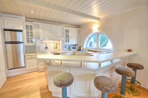 una cocina con armarios blancos y una barra con taburetes en Villa Skilift-Seeblick - by Alpen Apartments, en Zell am See