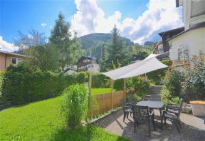 un patio con mesa, sillas y sombrilla en Villa Skilift-Seeblick - by Alpen Apartments, en Zell am See