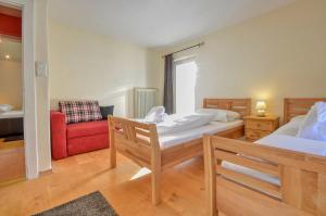 1 dormitorio con 2 camas y silla roja en Villa Skilift-Seeblick - by Alpen Apartments, en Zell am See