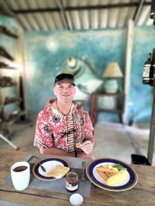 a man sitting at a table with a plate of food at Baan Hotelier Resort in Trat