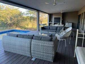 赫克托斯普雷特的住宿－Barn Owl Lodge, Mjejane Game Reserve, Greater Kruger Park，客厅设有一张沙发,甲板上配有椅子