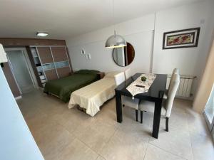 1 dormitorio con mesa, cama, mesa y sillas en Departamentos Eneas Frente al Mar en Mar del Plata